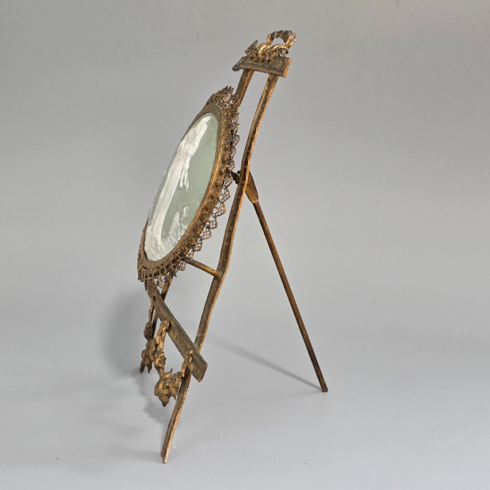 A pale green and white bisque porcelain oval plaque depicting two figures in high relief, supported on an ornate gilt metal easel. View III