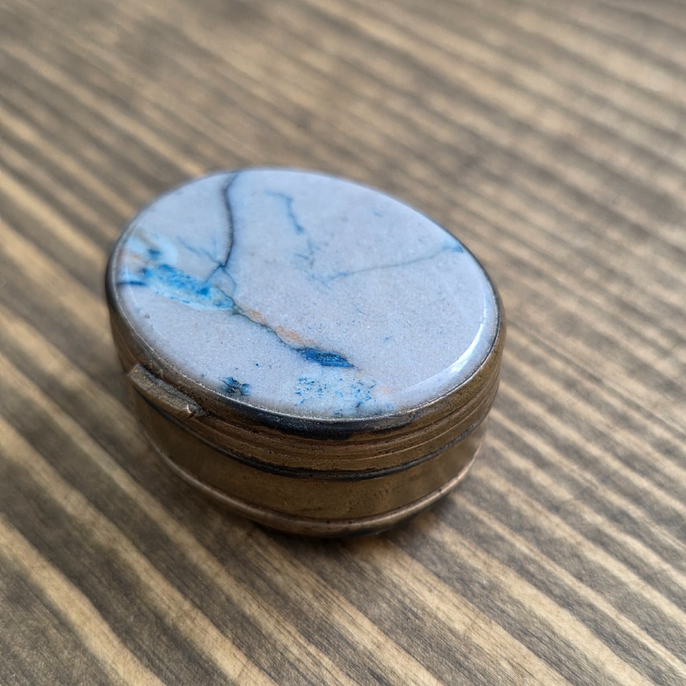 An oval Georgian gilt metal snuff box featuring a polished blue and grey banded agate stone inset on the lid.