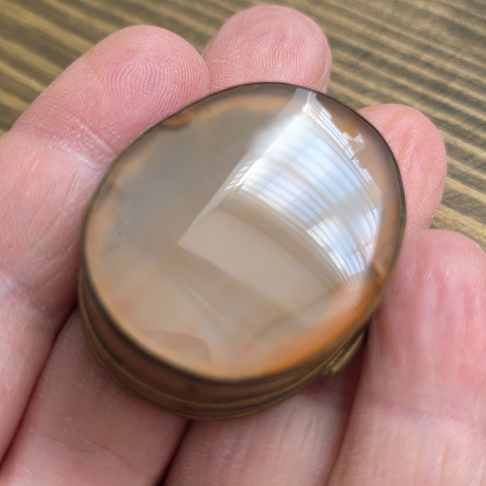 An oval Georgian gilt metal snuff box featuring a polished blue and grey banded agate stone inset on the lid. View IV