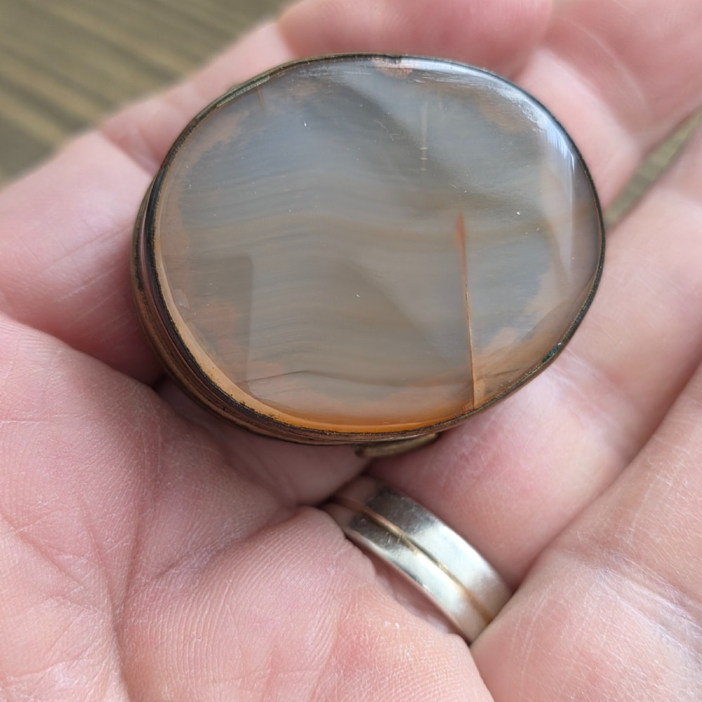 An oval Georgian gilt metal snuff box featuring a polished blue and grey banded agate stone inset on the lid. View VIII