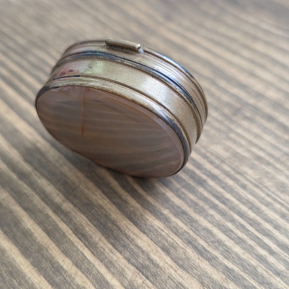 An oval Georgian gilt metal snuff box featuring a polished blue and grey banded agate stone inset on the lid. View IX