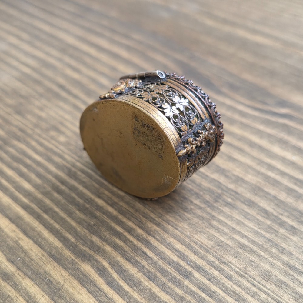 A small oval Victorian gilt metal pill box featuring a polished green moss agate cabochon lid and detailed relief scrollwork on the sides. View III