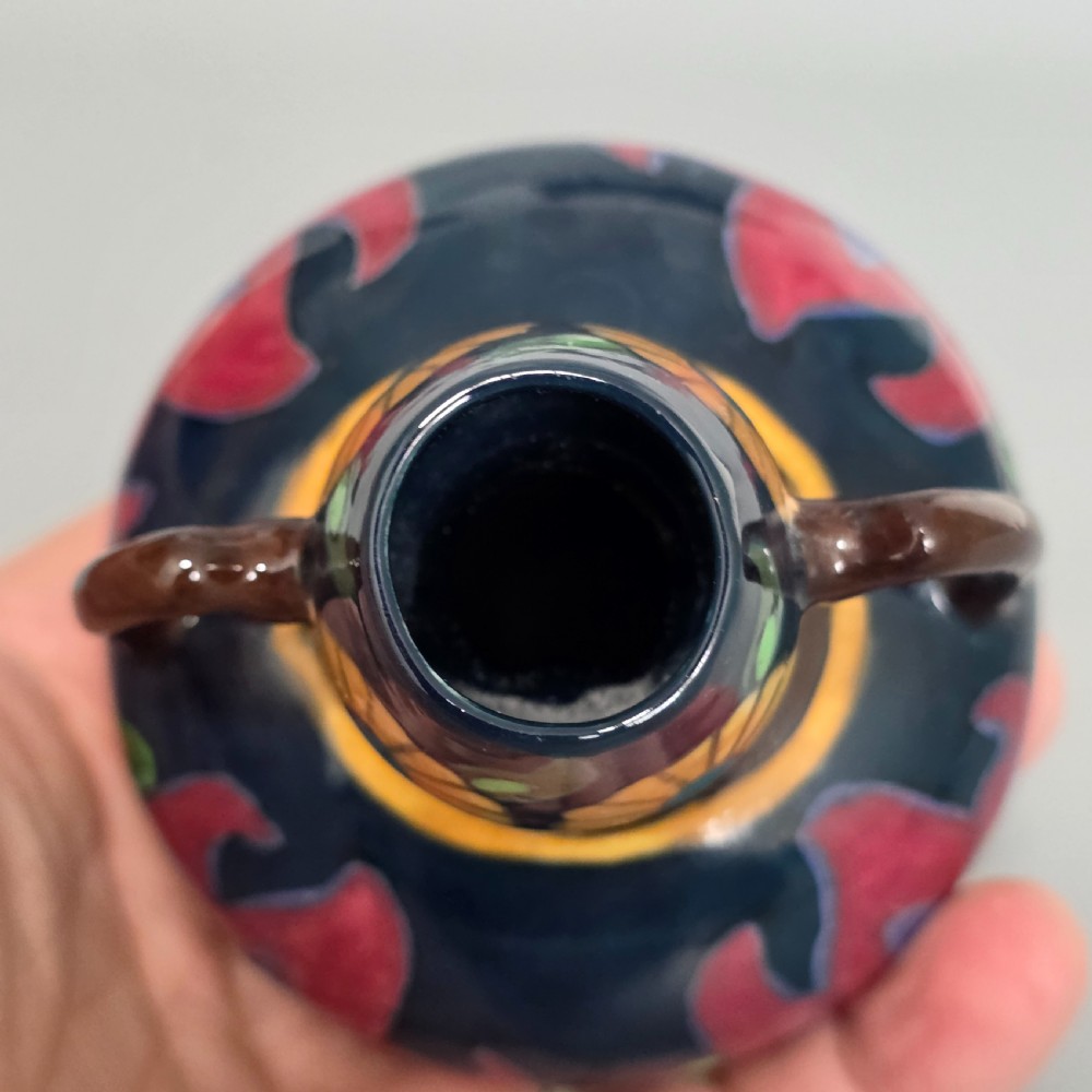 A glazed earthenware Art Nouveau vase with twin handles featuring a dark blue and brown ground decorated with stylised pink, purple, yellow, and green floral patterns. View VIII