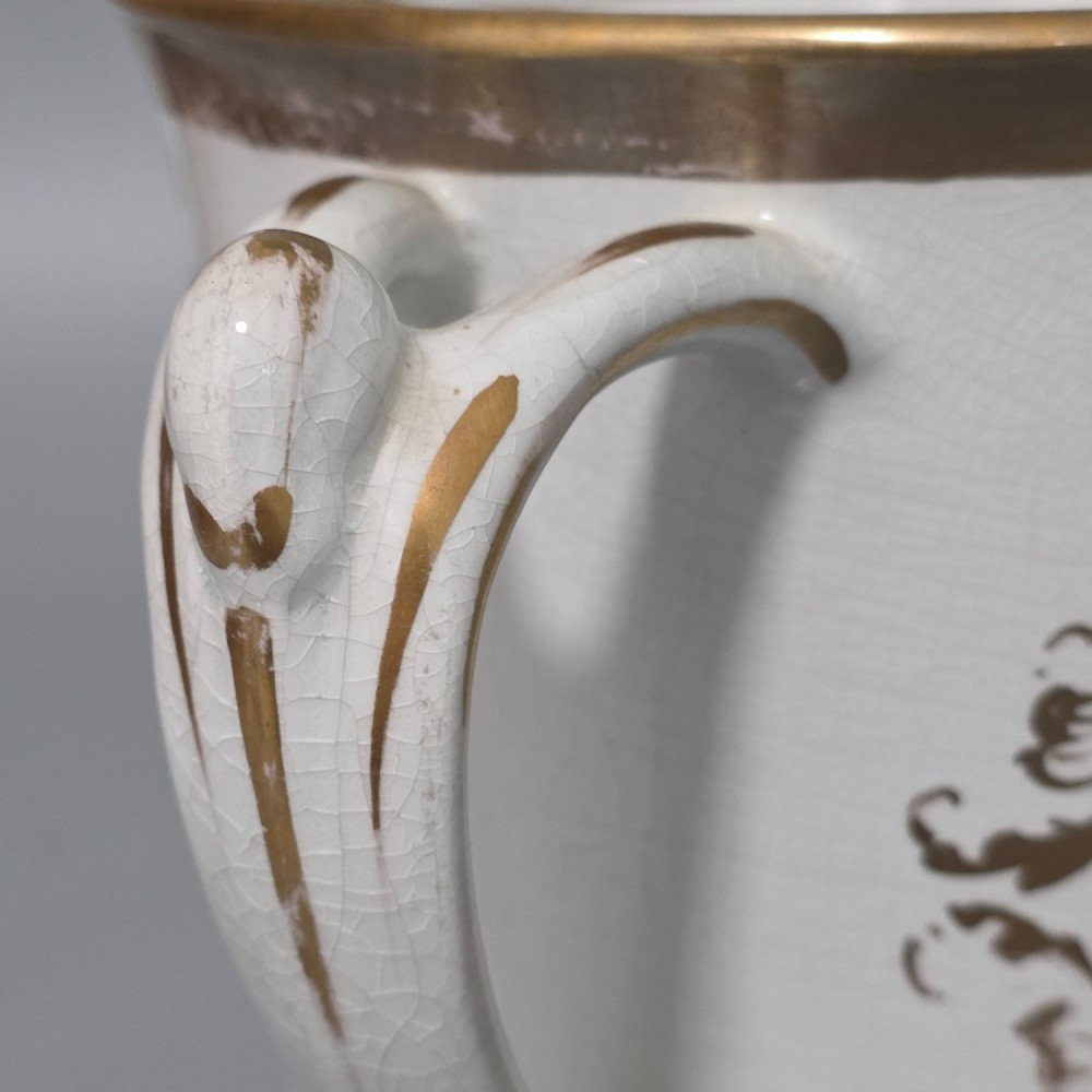 A nineteenth-century ceramic loving cup featuring two side handles, gilt trim, and a hand-painted landscape scene inside an oval cartouche. View X
