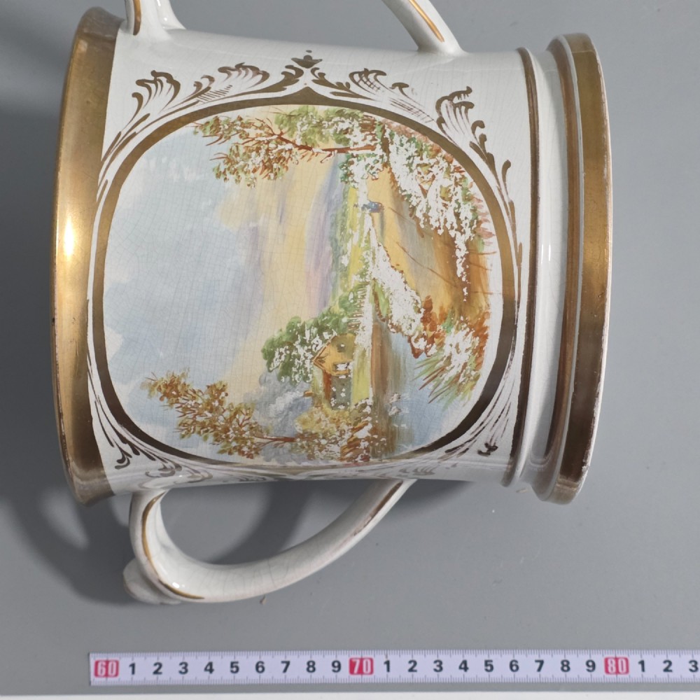 A nineteenth-century ceramic loving cup featuring two side handles, gilt trim, and a hand-painted landscape scene inside an oval cartouche. View XI