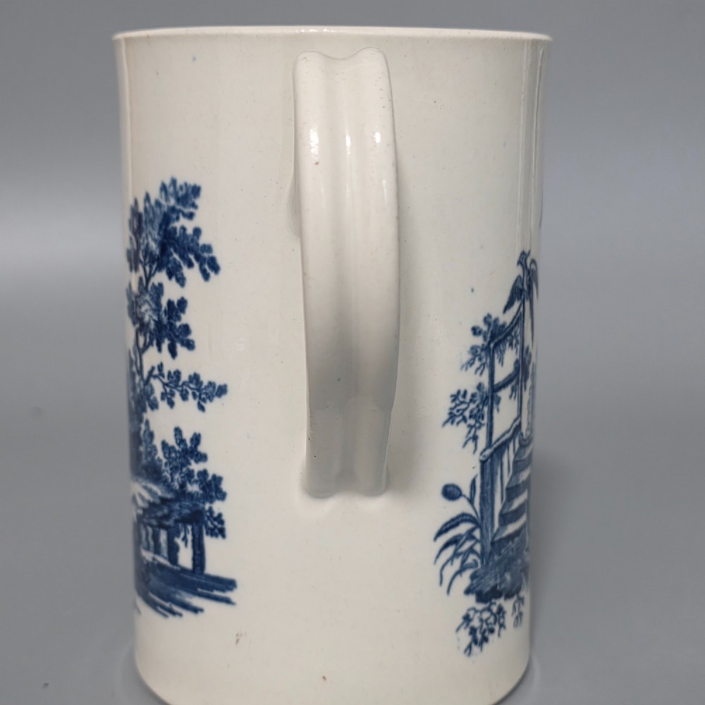 A tall cylindrical white porcelain mug featuring an 18th-century blue underglaze transfer-printed Chinoiserie design of figures and parasols with a single loop handle. View III