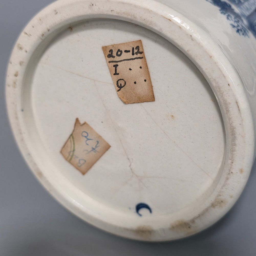 A tall cylindrical white porcelain mug featuring an 18th-century blue underglaze transfer-printed Chinoiserie design of figures and parasols with a single loop handle. View VIII
