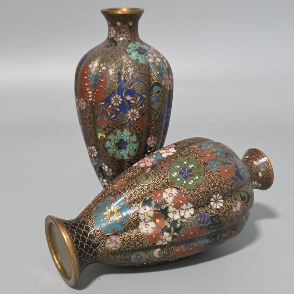 A pair of baluster-shaped Japanese cloisonne enamel vases decorated with intricate floral patterns, roundels, and scrollwork on a dark ground. View X
