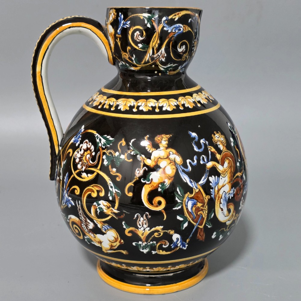 A nineteenth-century French Gien faience water pitcher featuring a black glazed body decorated with hand-painted ochre, white, and blue Renaissance revival mythological figures and scrolling foliage. View II