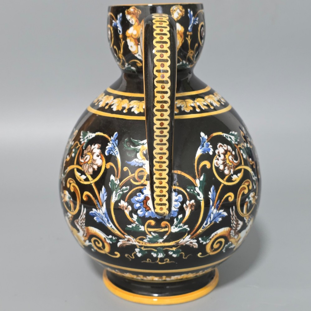 A nineteenth-century French Gien faience water pitcher featuring a black glazed body decorated with hand-painted ochre, white, and blue Renaissance revival mythological figures and scrolling foliage. View VIII