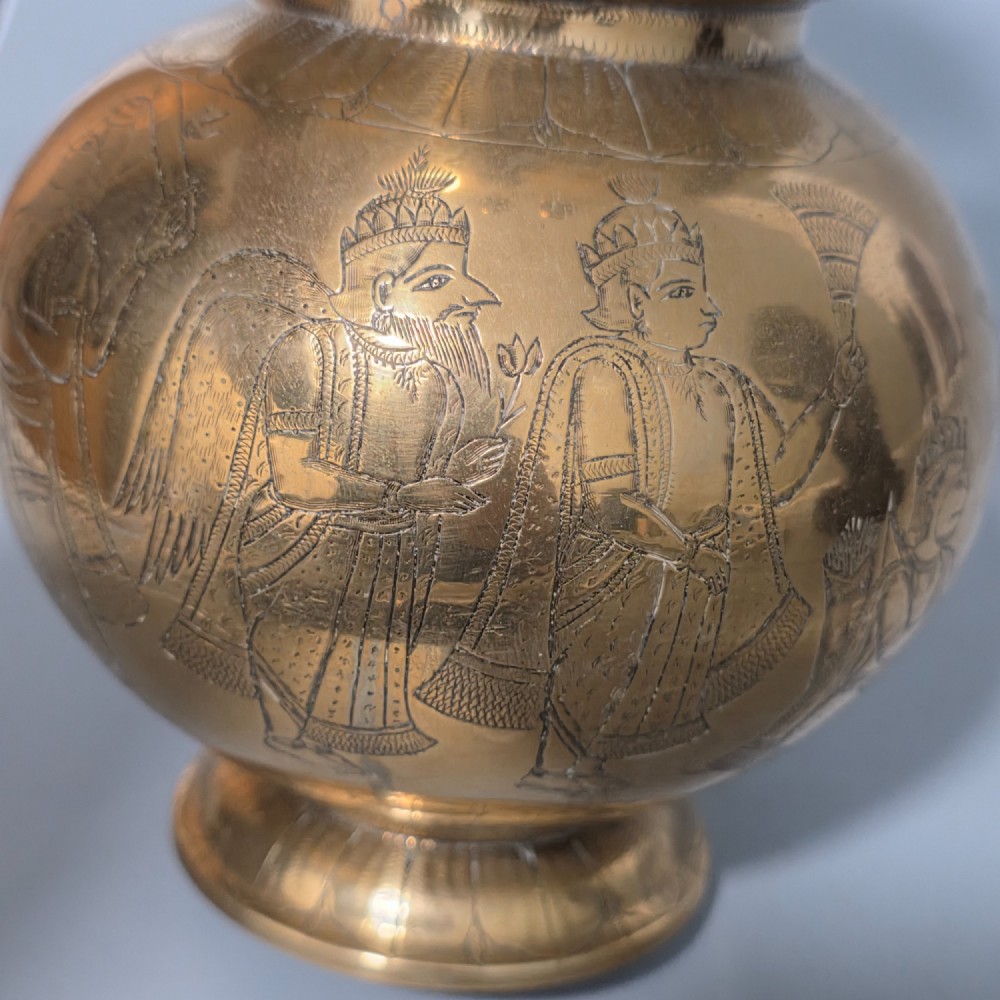 An antique Indian engraved brass kamandal vessel featuring a rounded base decorated with figures, a flared upper rim, and a high arched handle with raised knops. View VII