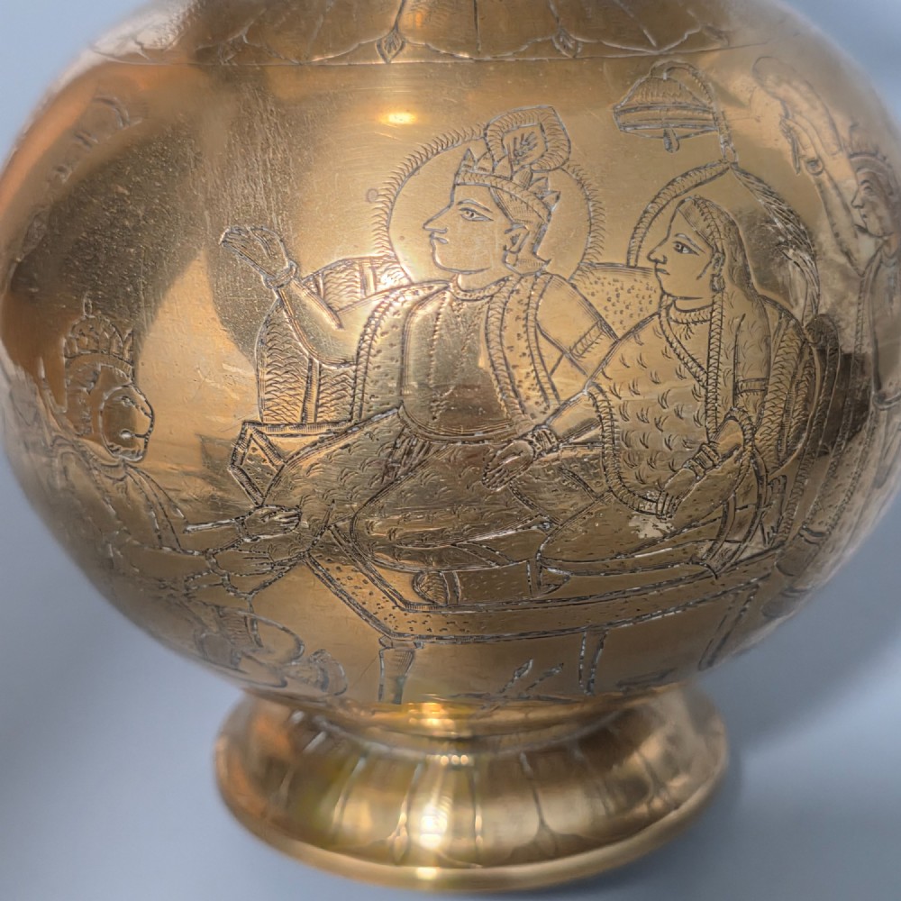 An antique Indian engraved brass kamandal vessel featuring a rounded base decorated with figures, a flared upper rim, and a high arched handle with raised knops. View VIII
