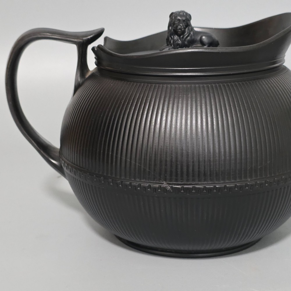 An 18th-century matte black basalt teapot featuring vertical engine-turned fluting, a curved spout, and a lid crowned with a sculpted lion finial. View III