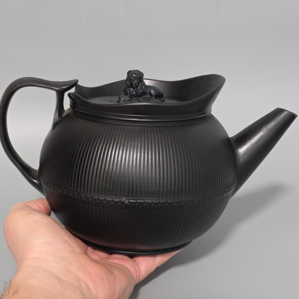An 18th-century matte black basalt teapot featuring vertical engine-turned fluting, a curved spout, and a lid crowned with a sculpted lion finial. View IV