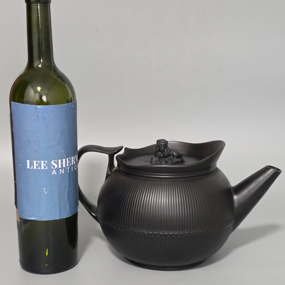 An 18th-century matte black basalt teapot featuring vertical engine-turned fluting, a curved spout, and a lid crowned with a sculpted lion finial. View V