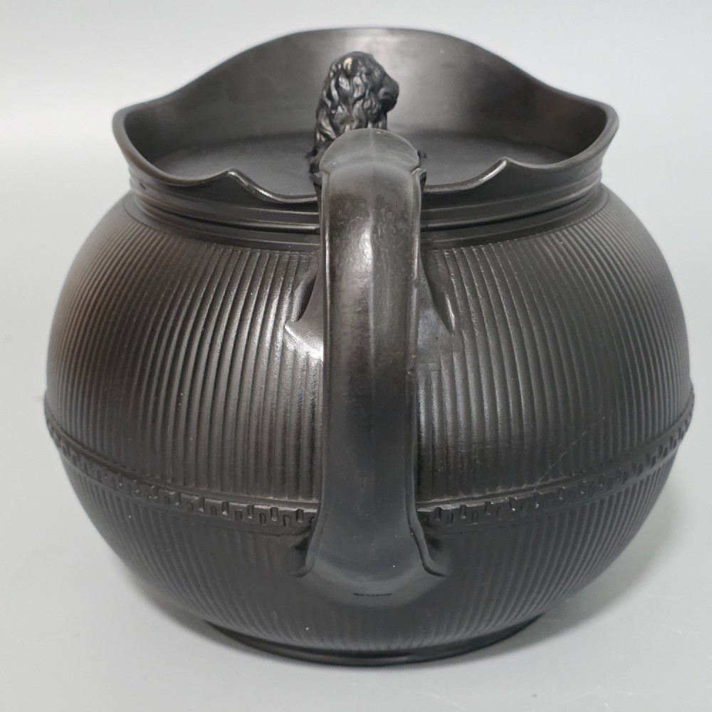 An 18th-century matte black basalt teapot featuring vertical engine-turned fluting, a curved spout, and a lid crowned with a sculpted lion finial. View XIII