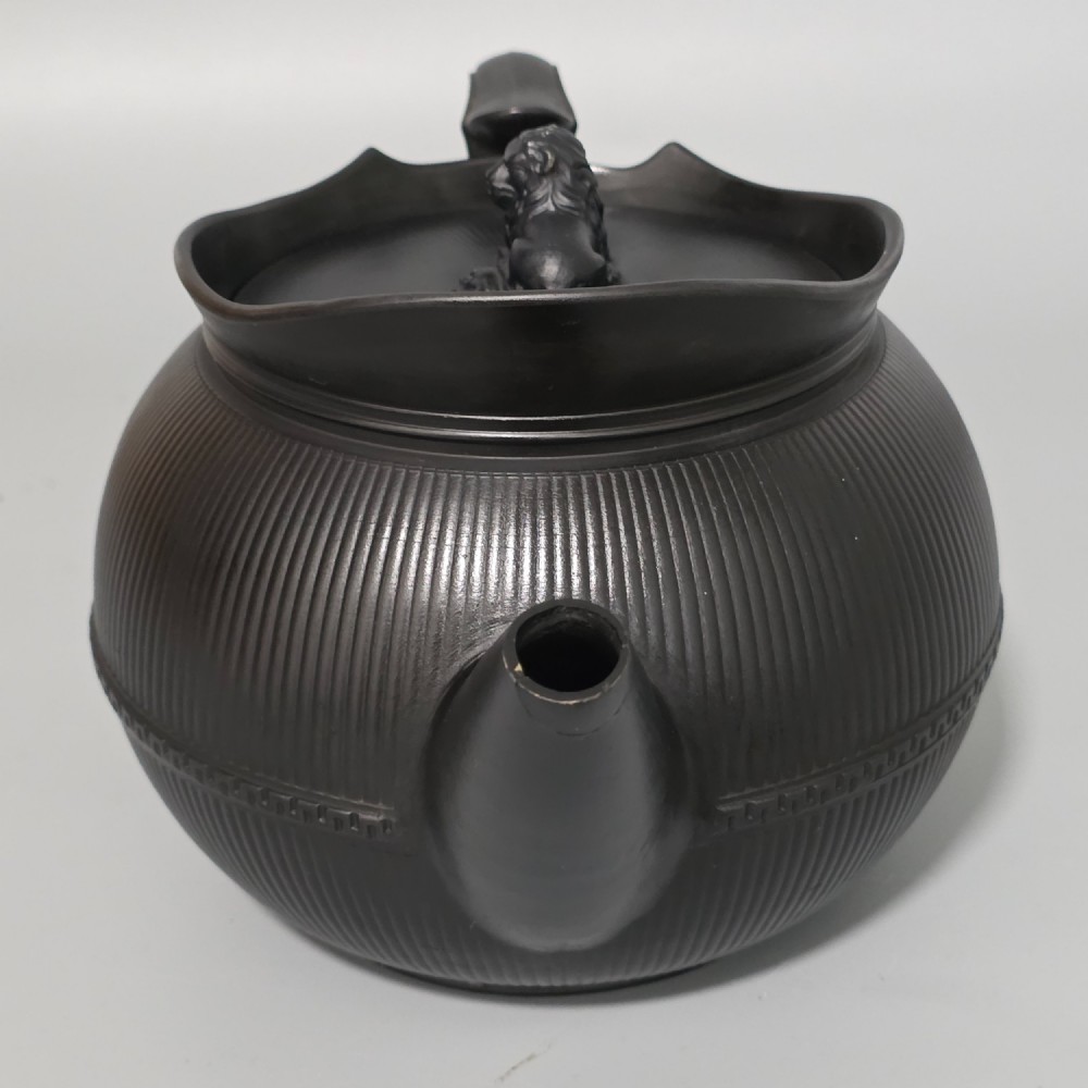 An 18th-century matte black basalt teapot featuring vertical engine-turned fluting, a curved spout, and a lid crowned with a sculpted lion finial. View XIV