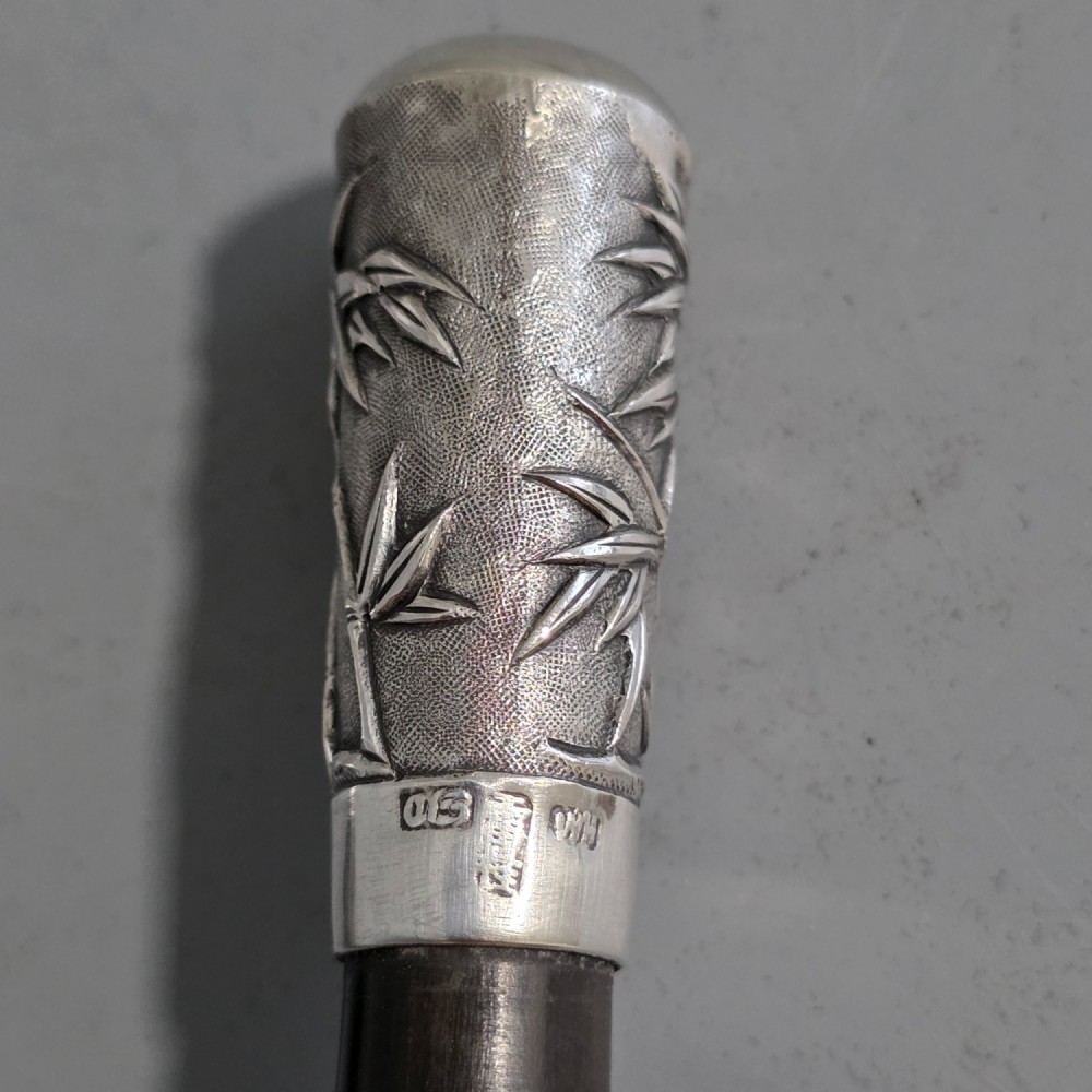 A pair of Chinese export silver salad servers featuring carved shell bowls, dark wooden bamboo-form handles, and silver terminal caps chased with bamboo leaves. View V