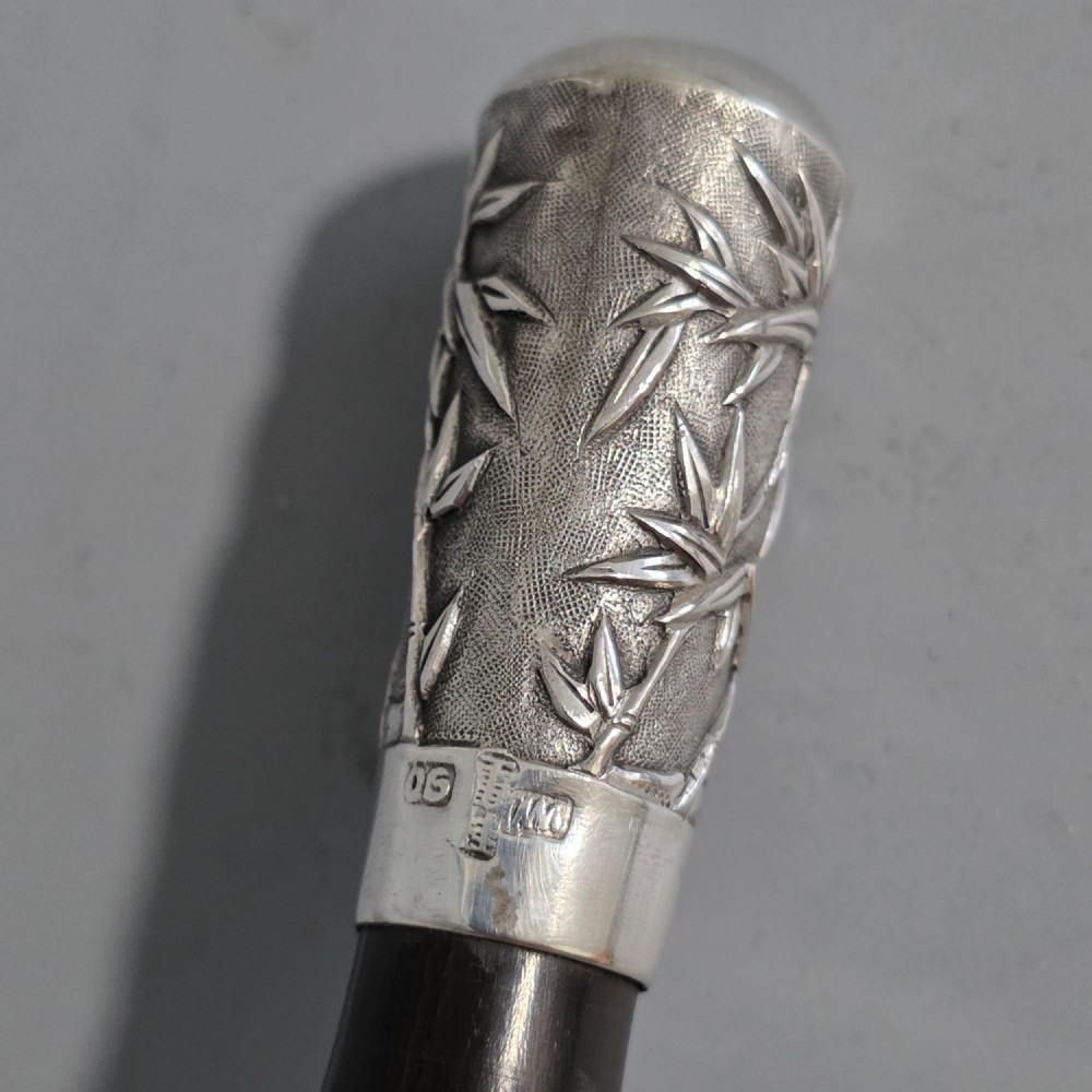 A pair of Chinese export silver salad servers featuring carved shell bowls, dark wooden bamboo-form handles, and silver terminal caps chased with bamboo leaves. View VI