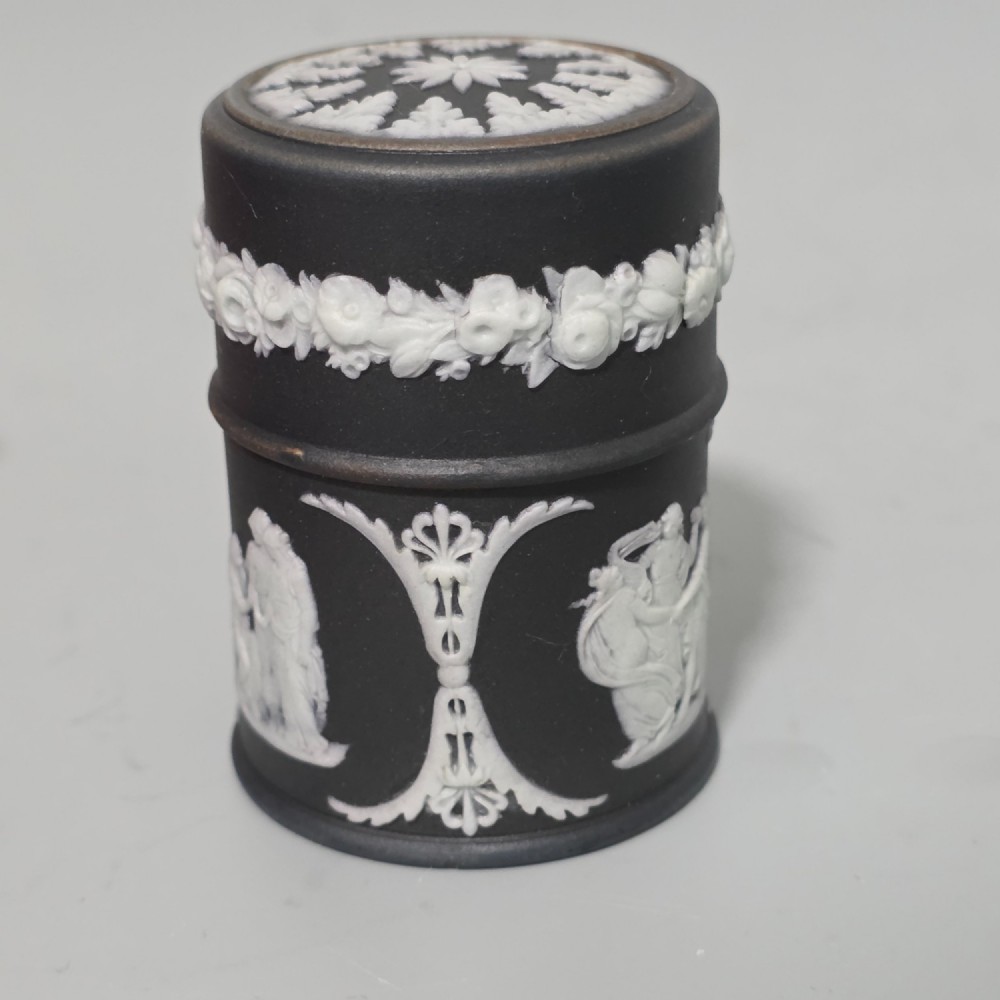 A cylindrical black stoneware Wedgwood match striker featuring white classical relief figures and floral garlands. View III