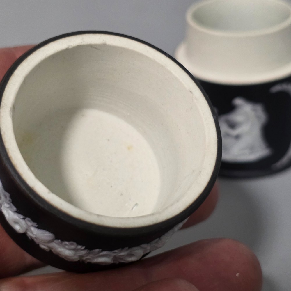 A cylindrical black stoneware Wedgwood match striker featuring white classical relief figures and floral garlands. View VI