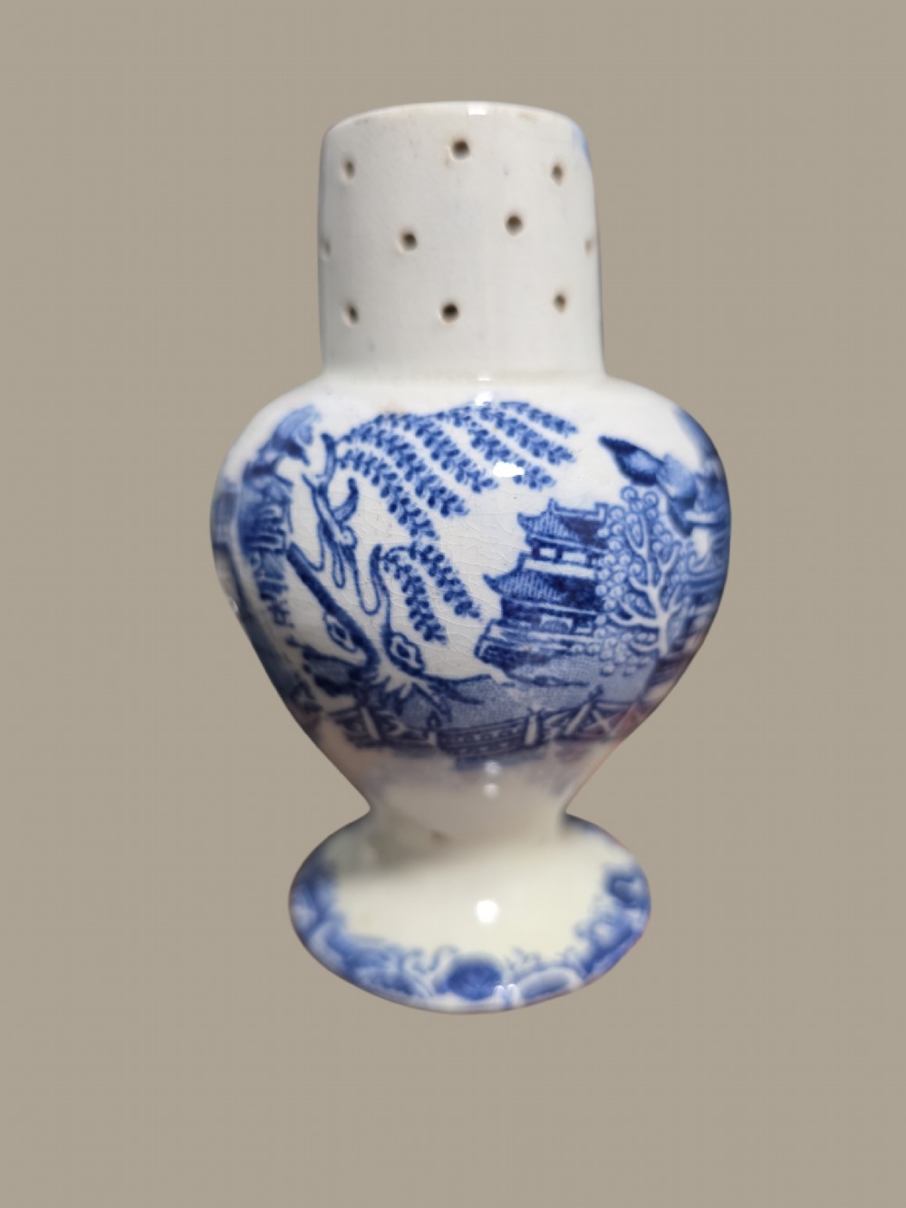 A small antique blue and white pearlware pepper pot with pierced holes on top and a transferware landscape pattern. View II