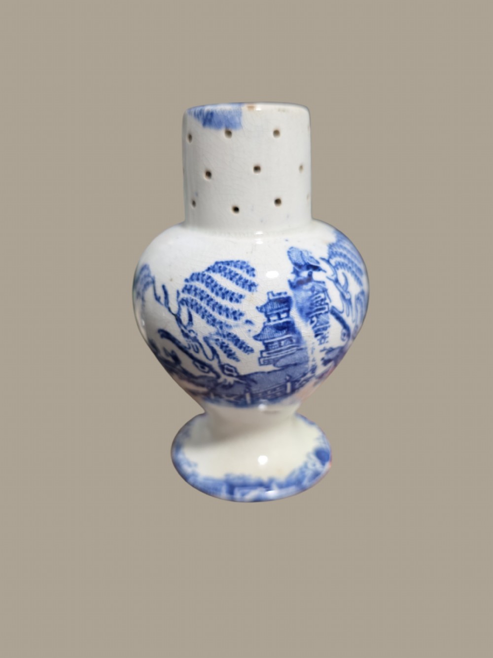 A small antique blue and white pearlware pepper pot with pierced holes on top and a transferware landscape pattern. View V