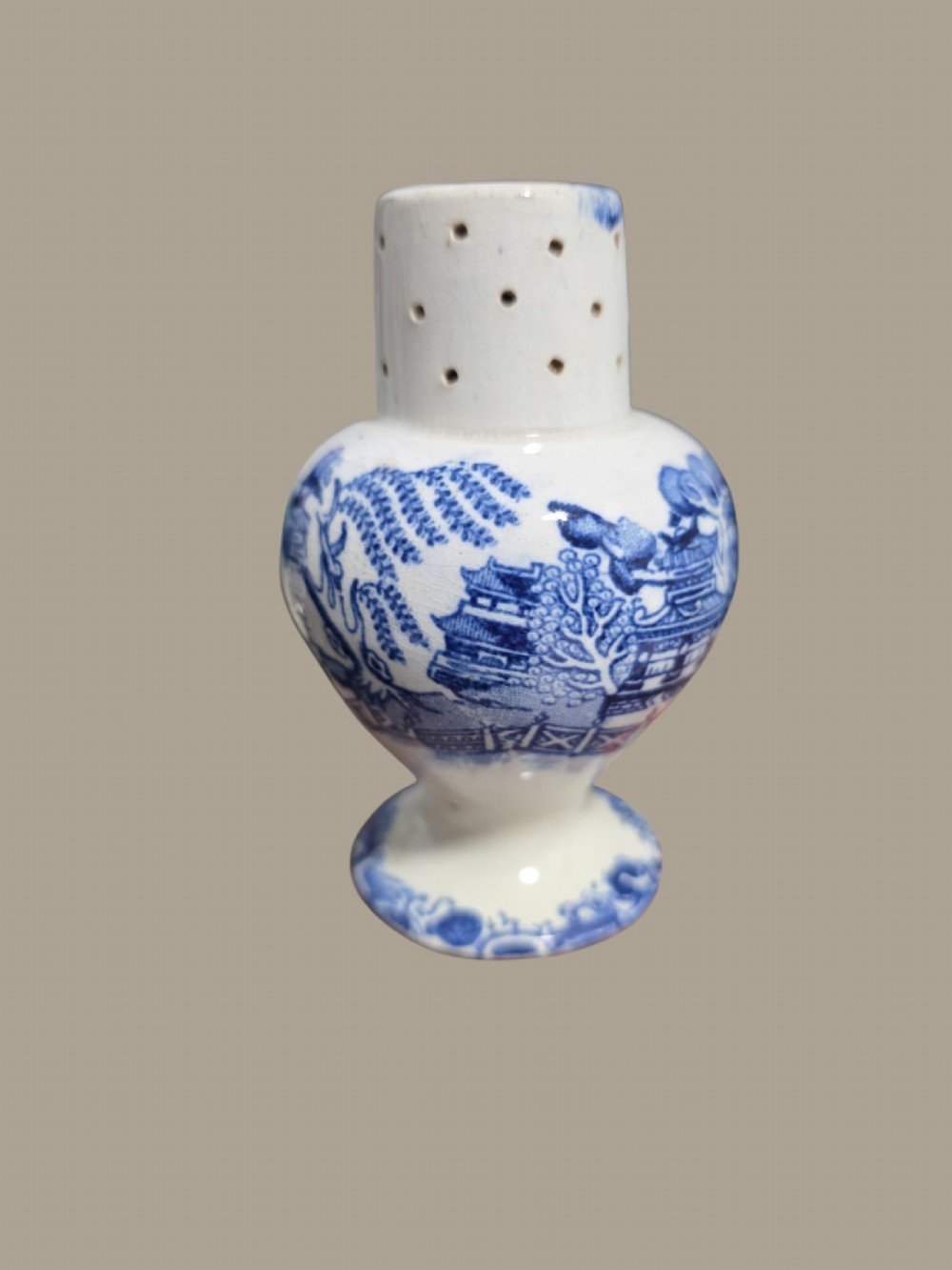 A small antique blue and white pearlware pepper pot with pierced holes on top and a transferware landscape pattern. View VI