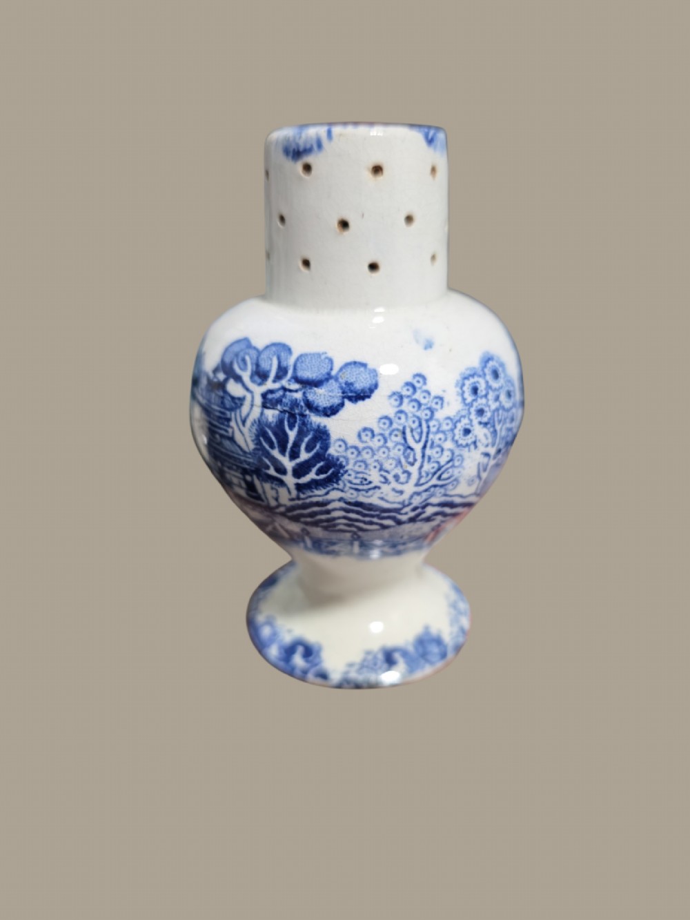 A small antique blue and white pearlware pepper pot with pierced holes on top and a transferware landscape pattern. View VII