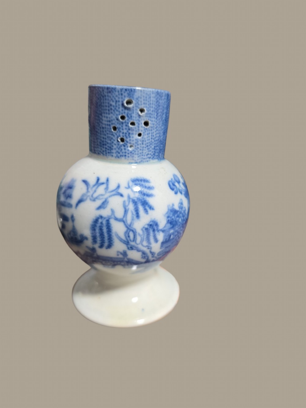 An antique blue and white pearlware pepper pot featuring transfer-printed chinoiserie motifs and a perforated cylindrical top. View V