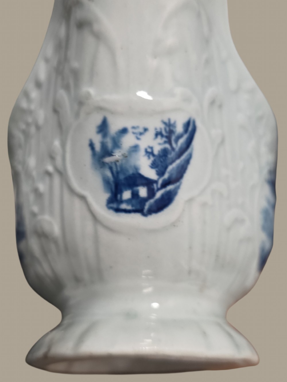 An eighteenth-century blue and white soft-paste porcelain sauce boat featuring moulded scroll decoration, a shaped rim, a scroll handle, and a printed landscape scene. View V
