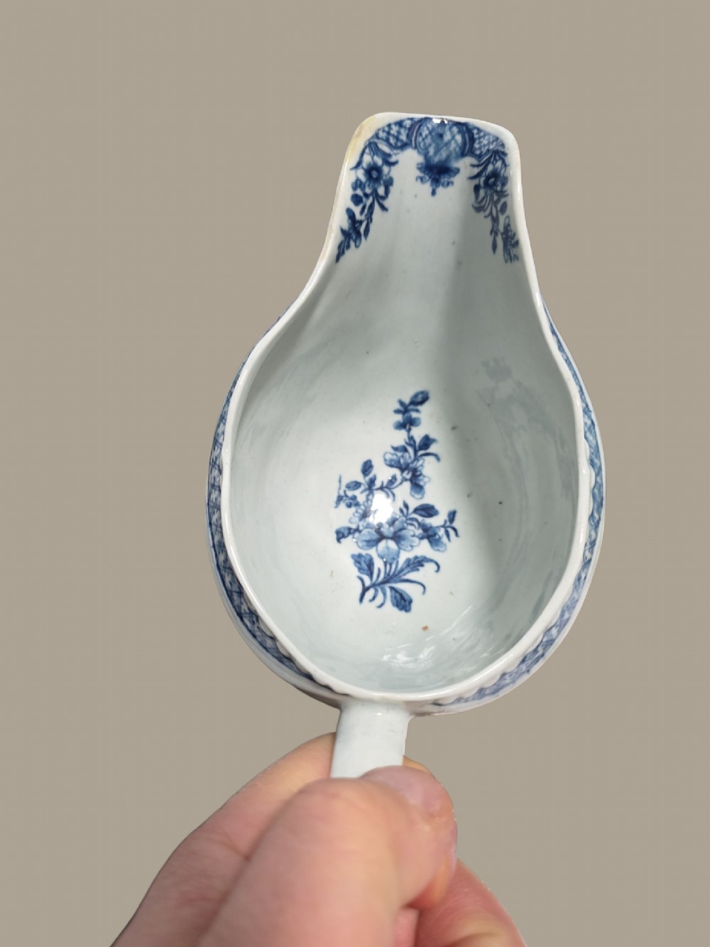 An eighteenth-century blue and white soft-paste porcelain sauce boat featuring moulded scroll decoration, a shaped rim, a scroll handle, and a printed landscape scene. View XI