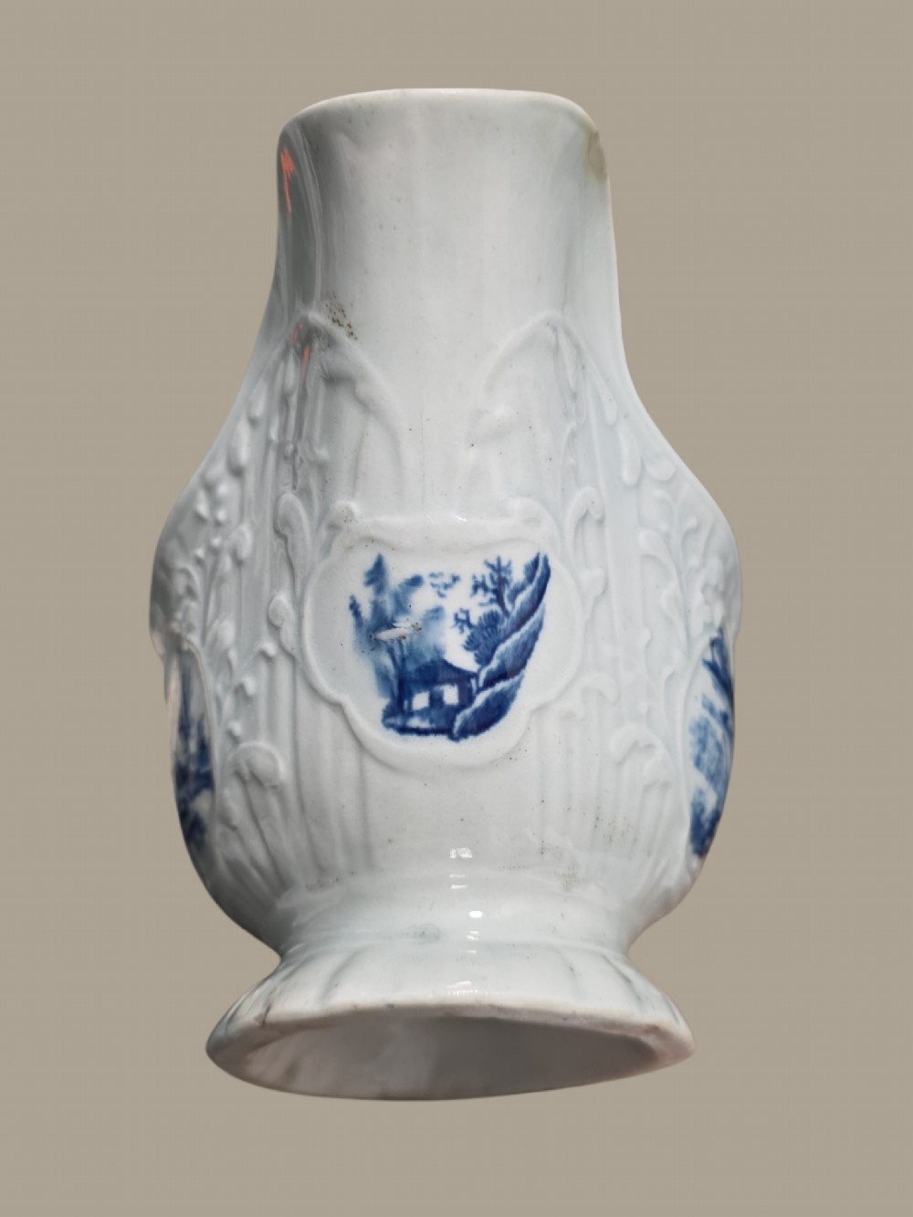 An eighteenth-century blue and white soft-paste porcelain sauce boat featuring moulded scroll decoration, a shaped rim, a scroll handle, and a printed landscape scene. View XII