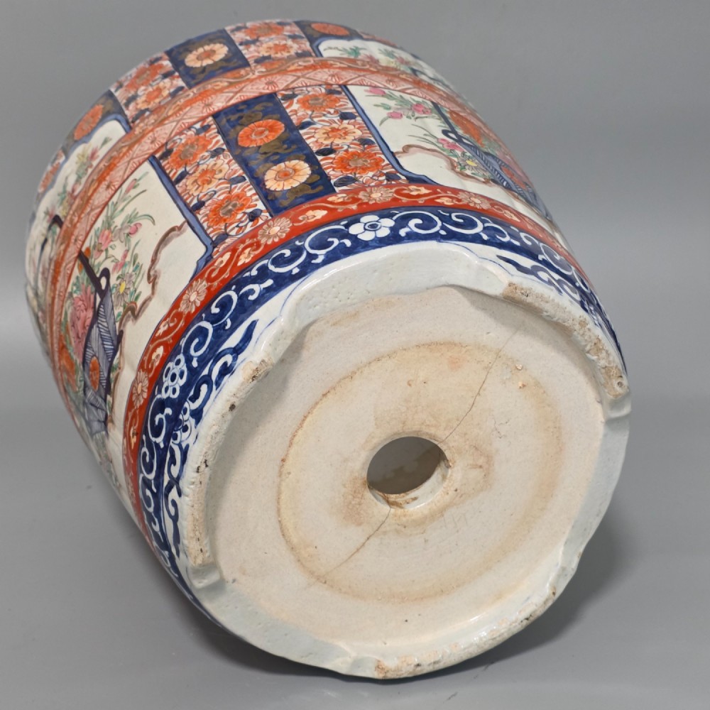 A late 19th-century Japanese Imari porcelain planter decorated with cobalt blue and iron-red floral basket panels, resting on a carved dark wood stand. View XII