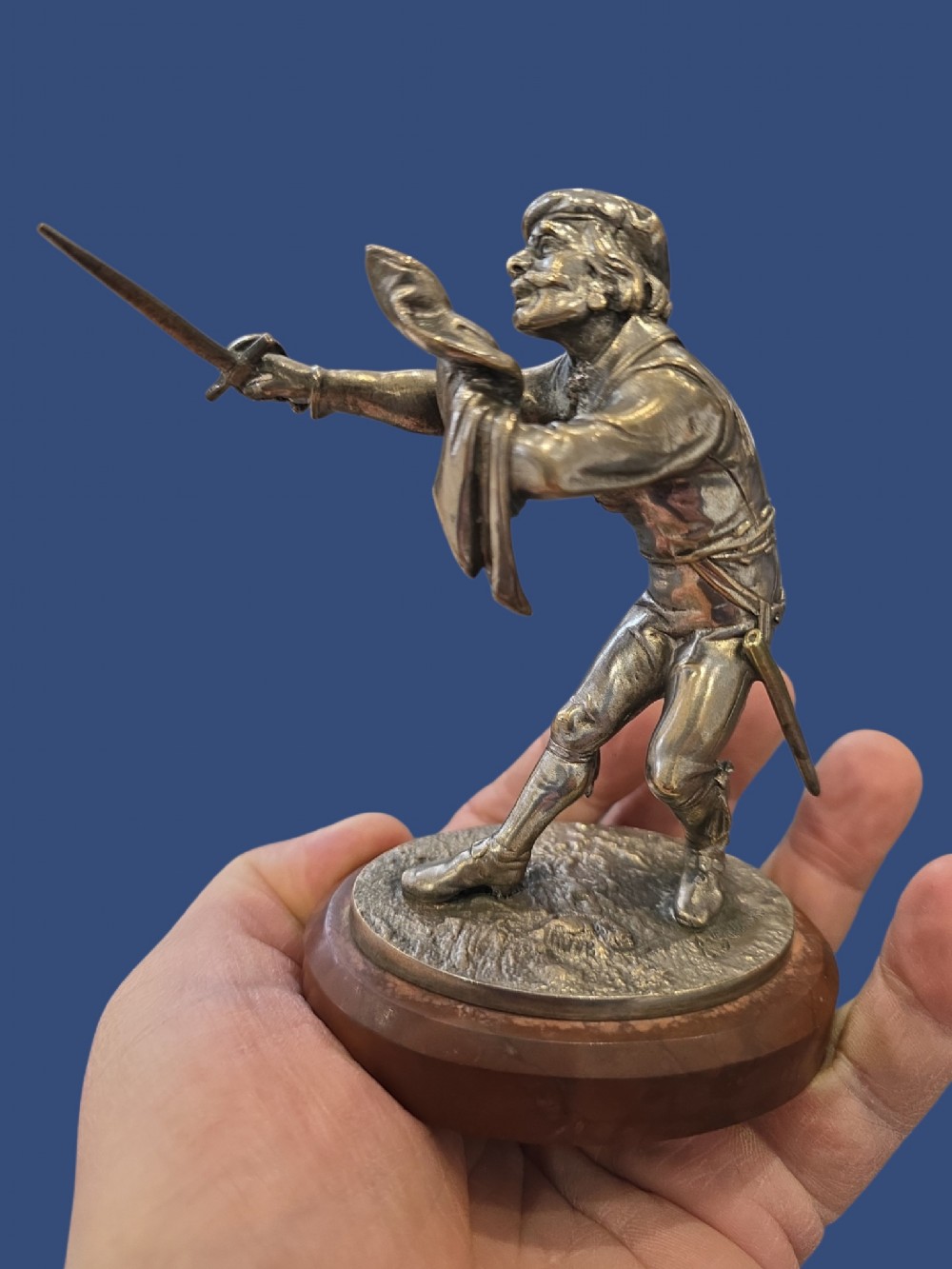 A nineteenth-century silvered bronze sculpture depicting a sword-wielding cavalier posed on an oval rouge marble plinth. View V