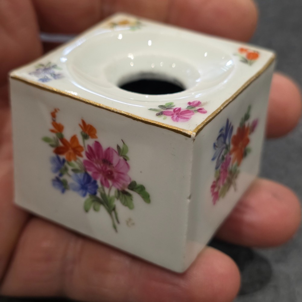 A square white porcelain inkwell featuring a recessed circular top, hand-painted botanical flowers on the sides, and a gold gilded rim. View IX