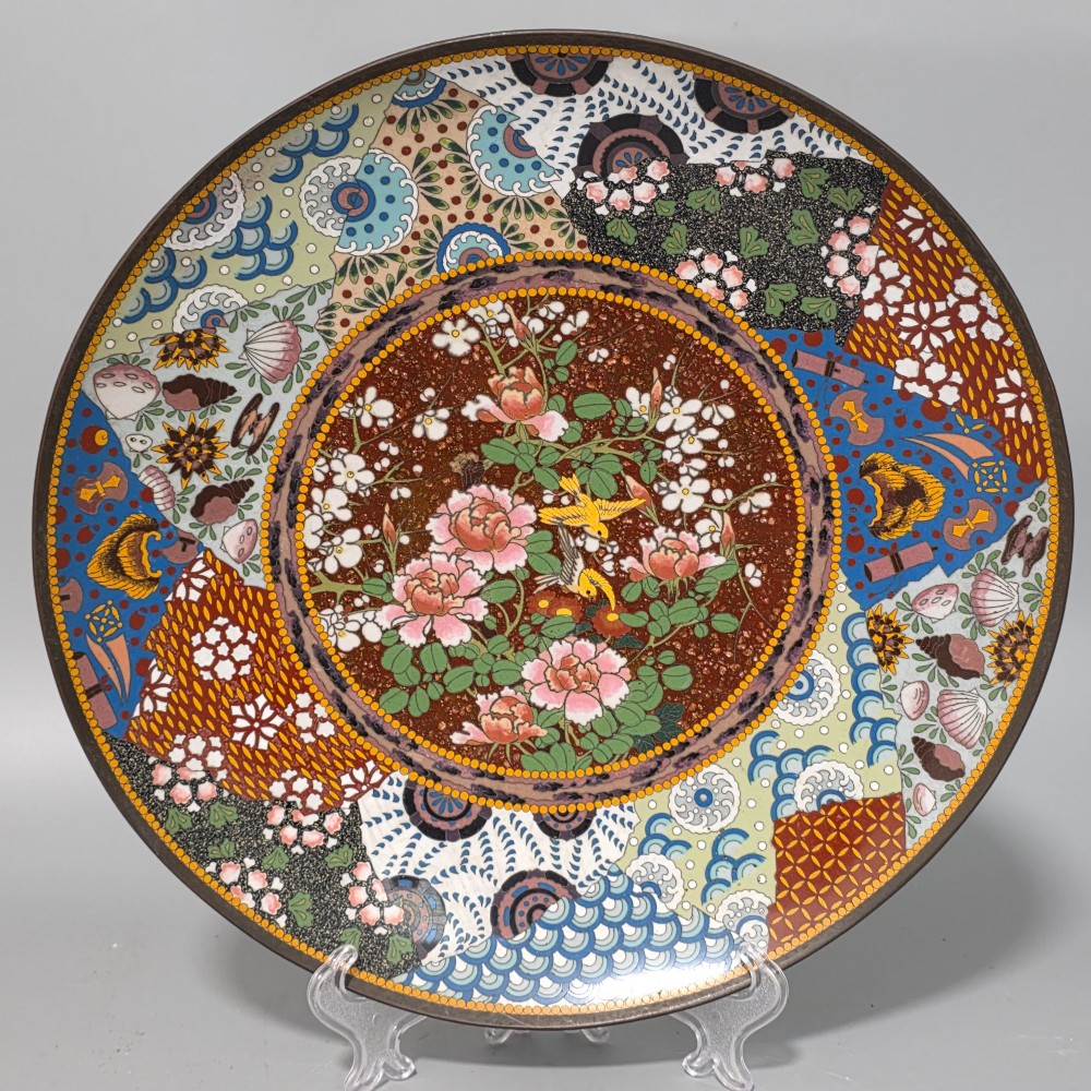 A circular Japanese cloisonne charger featuring a central medallion with birds and peonies on a brown aventurine background surrounded by patterned brocade sections.