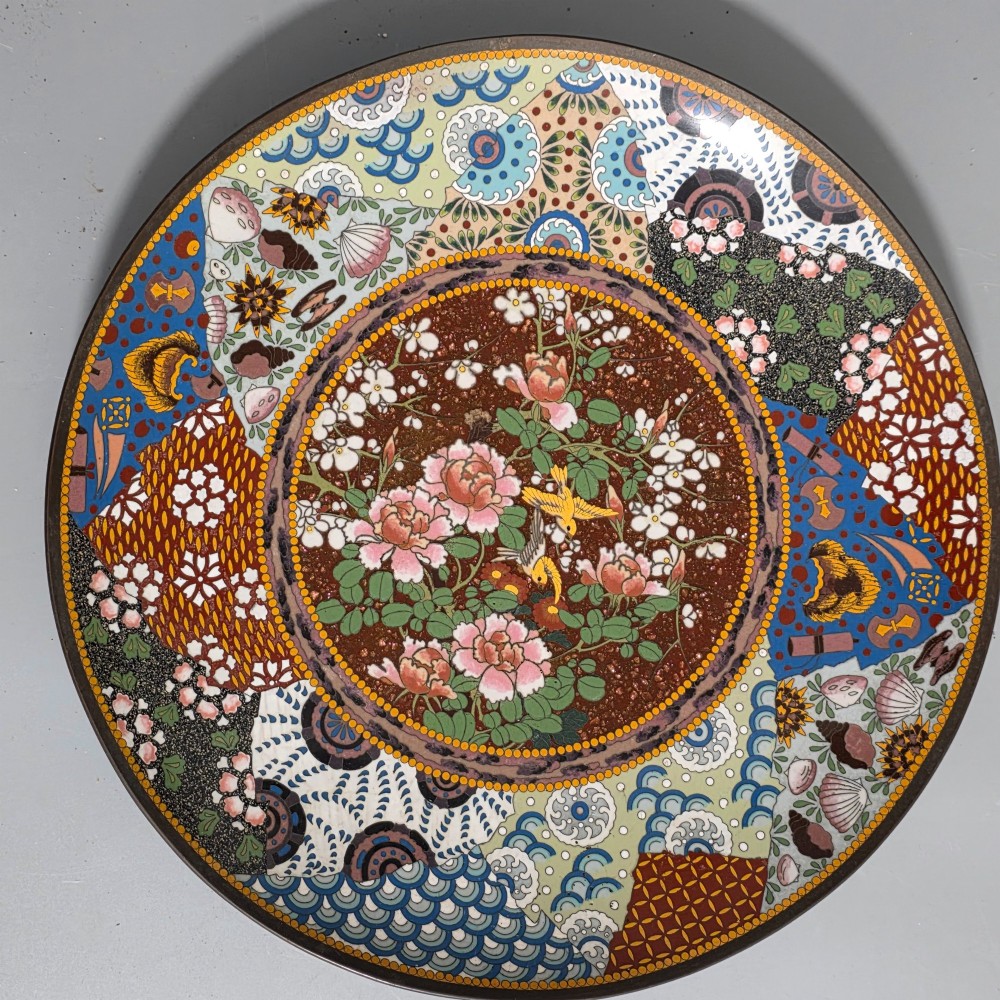 A circular Japanese cloisonne charger featuring a central medallion with birds and peonies on a brown aventurine background surrounded by patterned brocade sections. View II