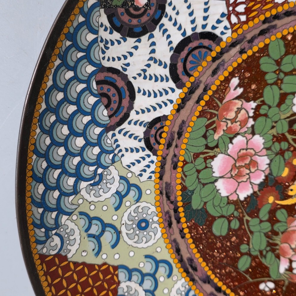 A circular Japanese cloisonne charger featuring a central medallion with birds and peonies on a brown aventurine background surrounded by patterned brocade sections. View VI