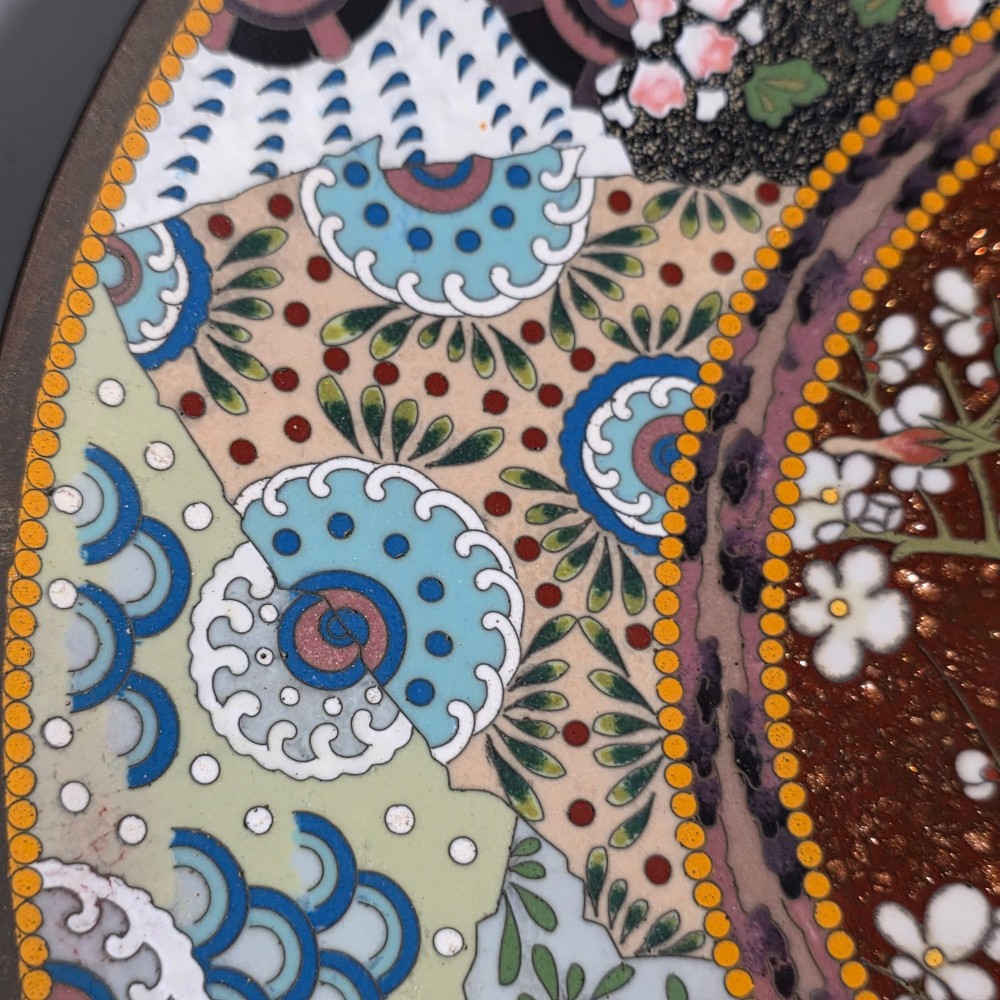 A circular Japanese cloisonne charger featuring a central medallion with birds and peonies on a brown aventurine background surrounded by patterned brocade sections. View XIII