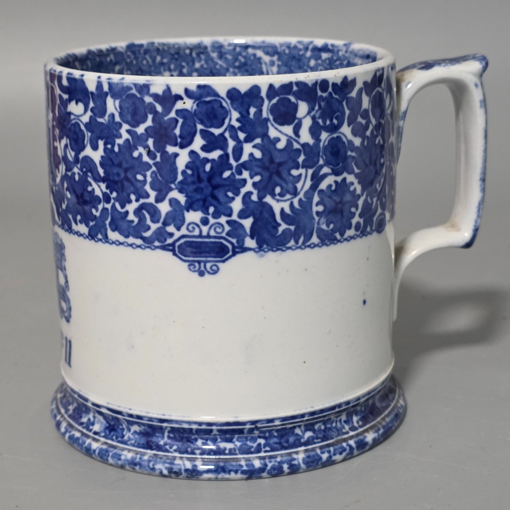 A cylindrical blue and white transferware ceramic tankard featuring a floral upper border and a coat of arms crest with the text No 11. View VIII