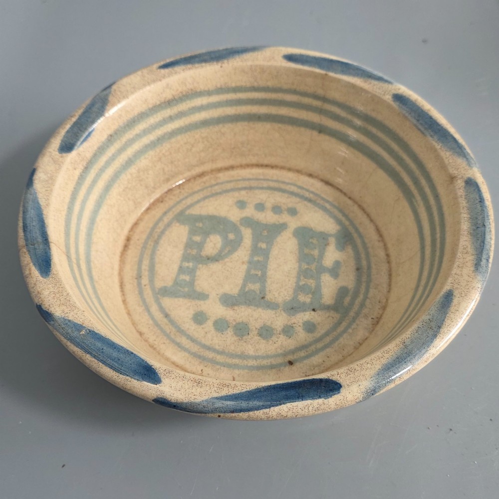 A circular nineteenth-century cream earthenware pie dish featuring the word PIE in blue lettering at the centre and blue decorative rim slashes.