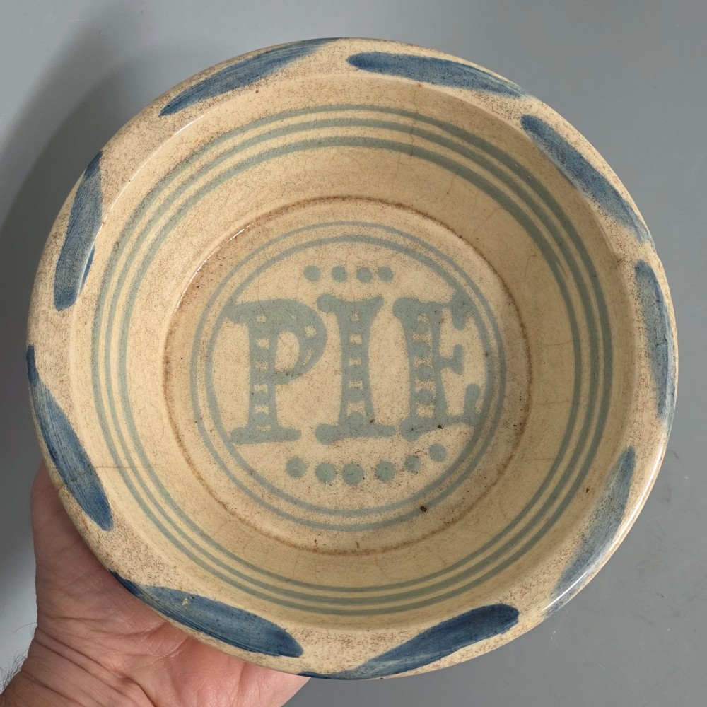 A circular nineteenth-century cream earthenware pie dish featuring the word PIE in blue lettering at the centre and blue decorative rim slashes. View III