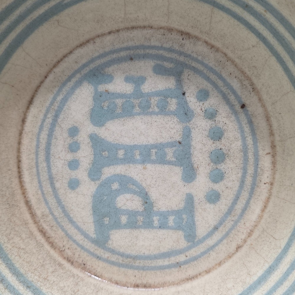A circular nineteenth-century cream earthenware pie dish featuring the word PIE in blue lettering at the centre and blue decorative rim slashes. View IV