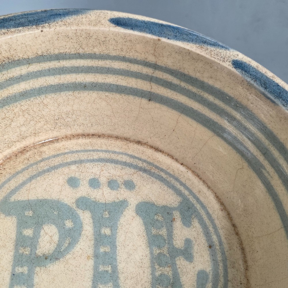 A circular nineteenth-century cream earthenware pie dish featuring the word PIE in blue lettering at the centre and blue decorative rim slashes. View VIII