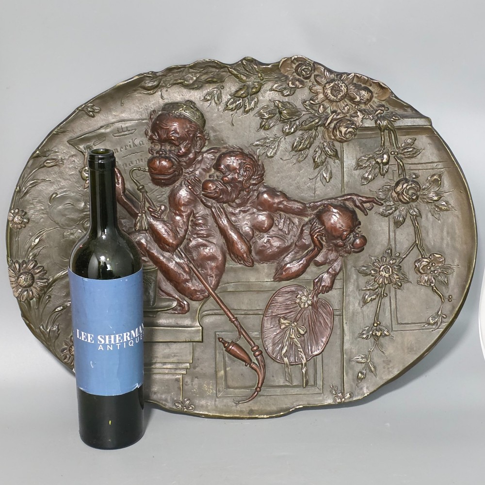 An oval dark brown Austrian terracotta relief plaque depicting a satirical scene of an anthropomorphic monkey family framed by relief floral motifs. View VIII