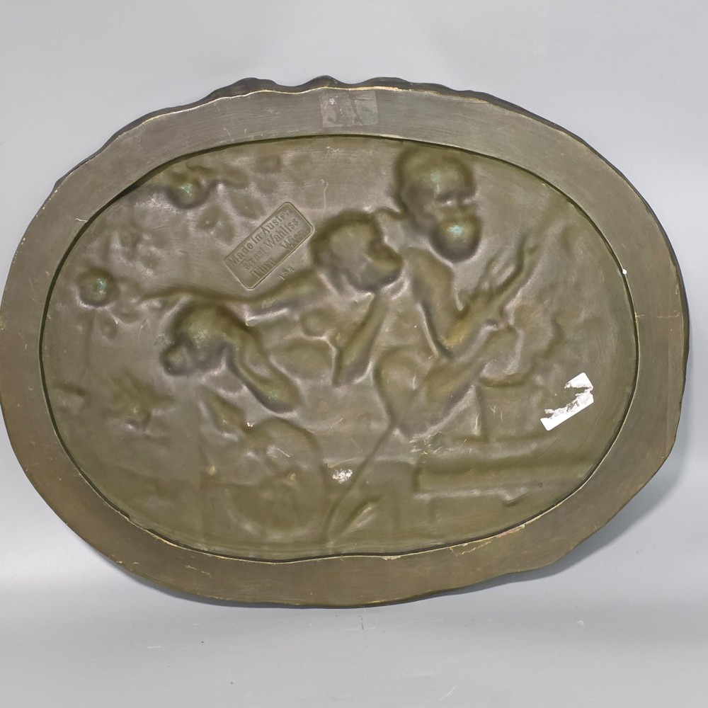An oval dark brown Austrian terracotta relief plaque depicting a satirical scene of an anthropomorphic monkey family framed by relief floral motifs. View X