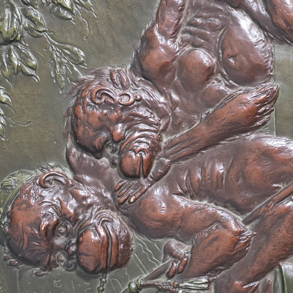 An oval dark brown Austrian terracotta relief plaque depicting a satirical scene of an anthropomorphic monkey family framed by relief floral motifs. View XIII