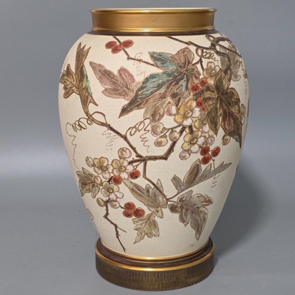 A large cream ceramic vase adorned with hand-painted botanical vines, foliage, berries, and gilded accents.