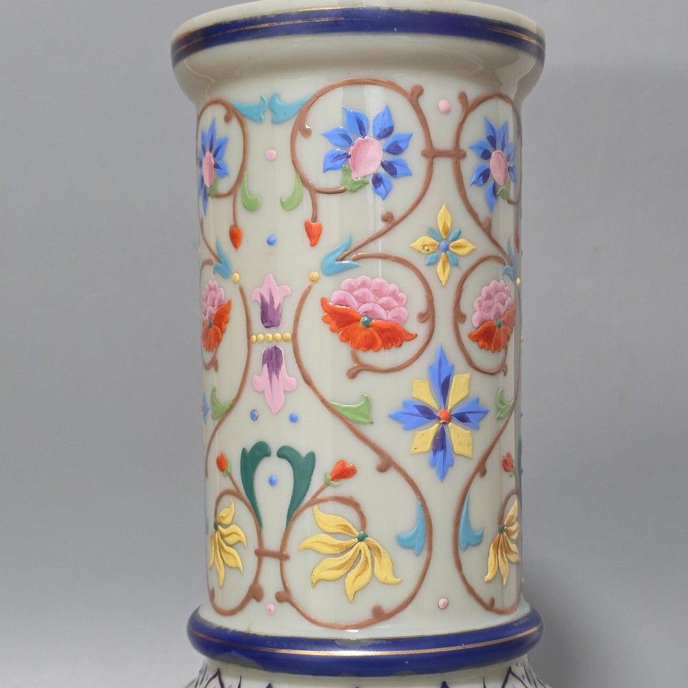 An antique cream opaque glass vase featuring hand-painted floral arabesque enamel patterns in bright colours with gilded accents and cobalt blue bands. View V
